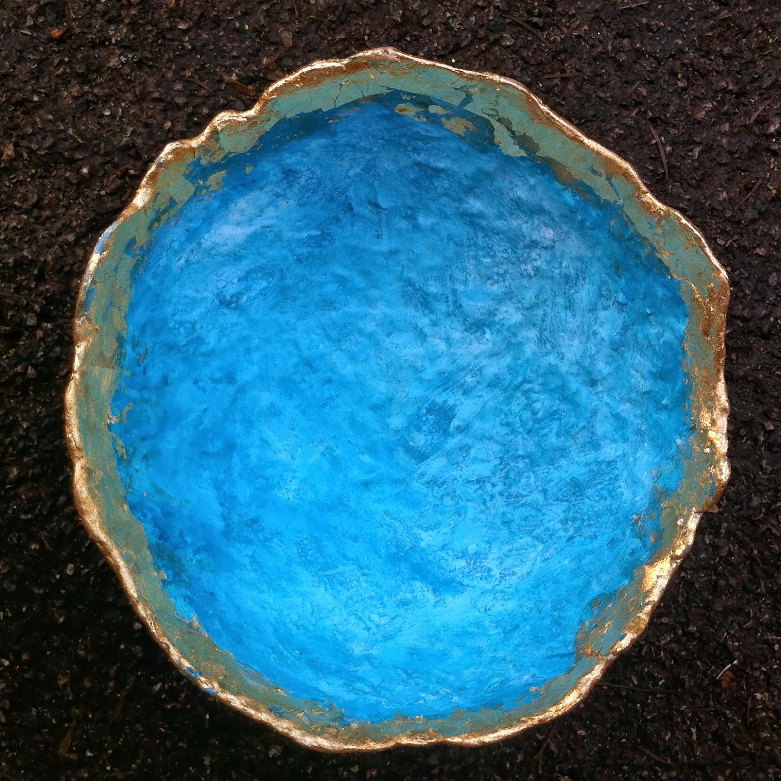A vivid blue paper mache bowl edged with gold