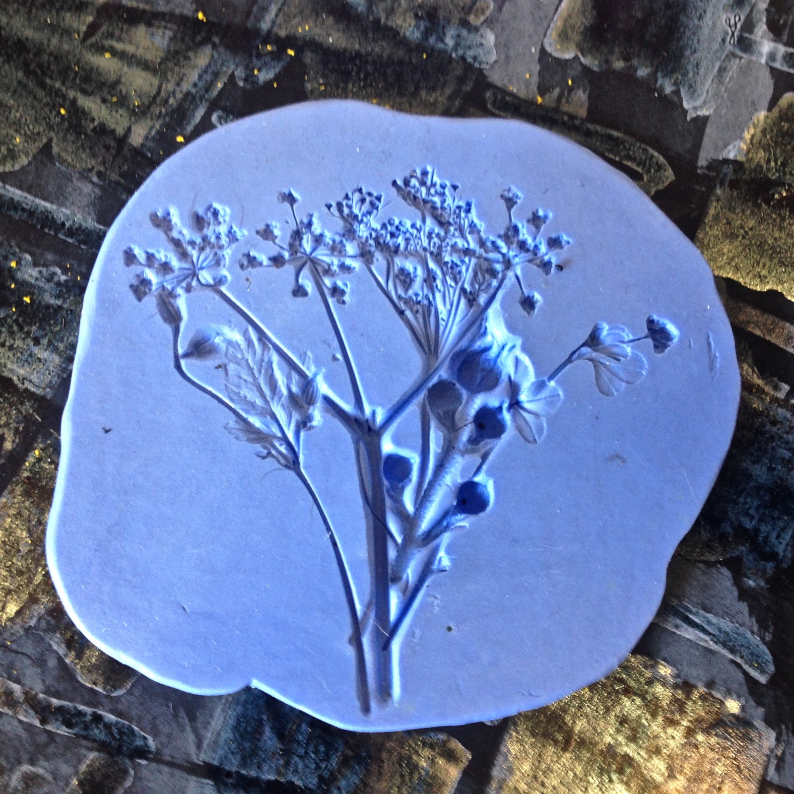 A blue flexible mould holding the impression of small flowers